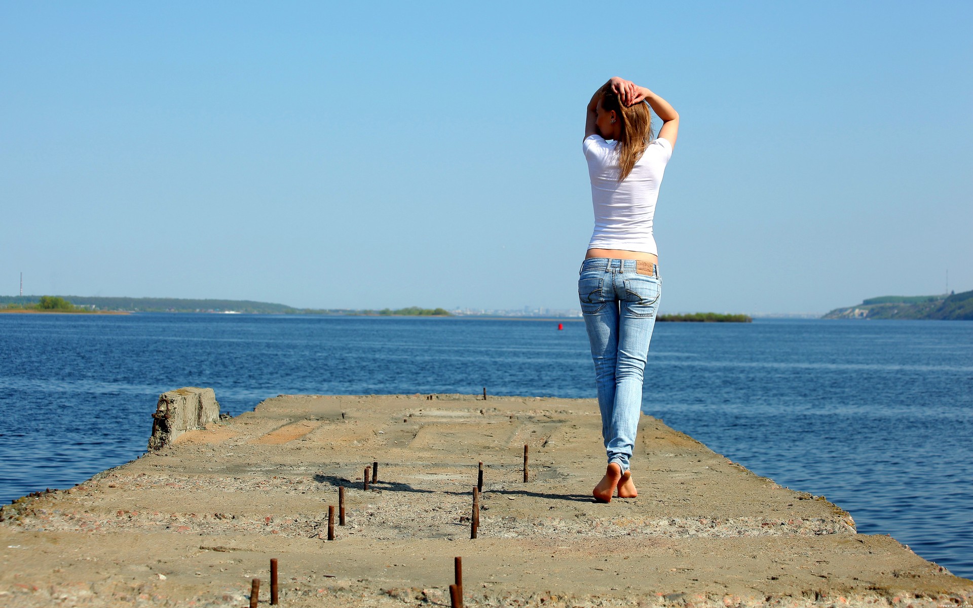 Девушка снимает джинсы на берегу моря